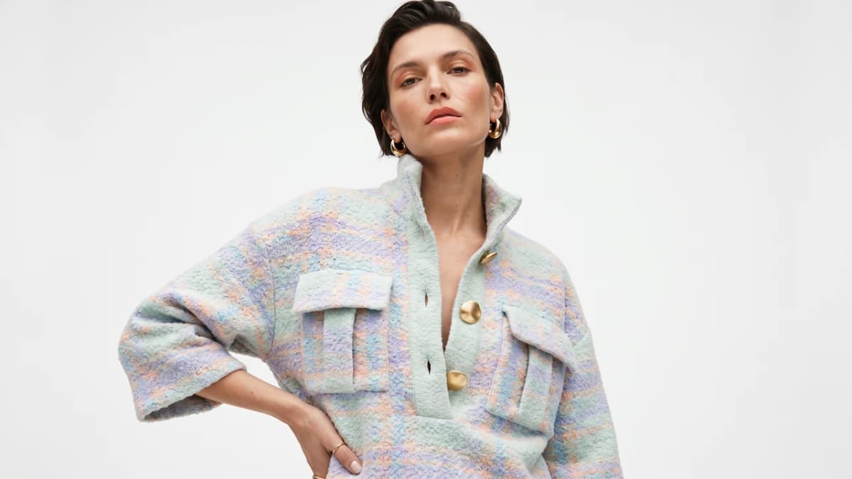 A model in a pastel tweed pullover with gold buttons