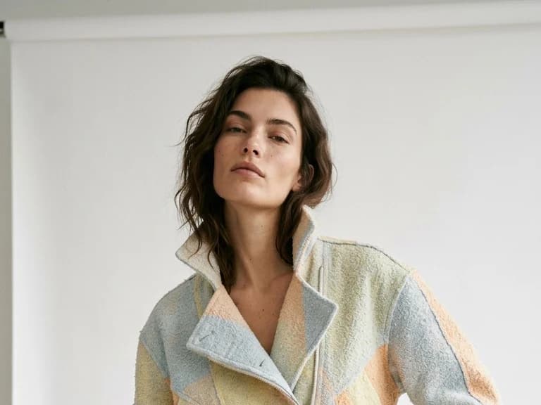 A model in a cropped pastel color block jacket and cream wide leg trousers, created inside one brand's workspace