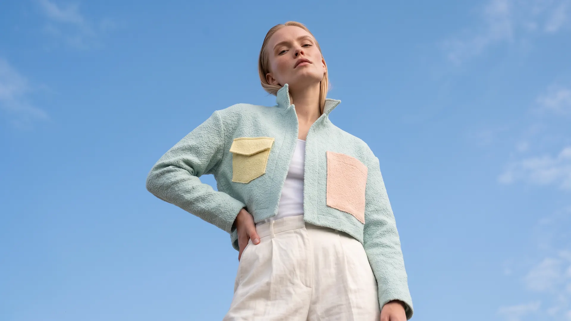 Model in a pastel colour-block jacket against a blue sky