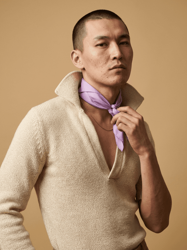 Male model adjusting a lilac silk scarf over a knit cardigan