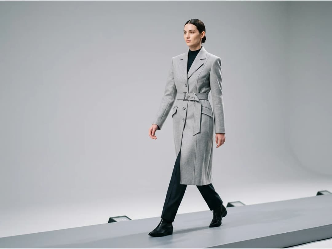 a model walking a fashion show runway, a tailored coat look
