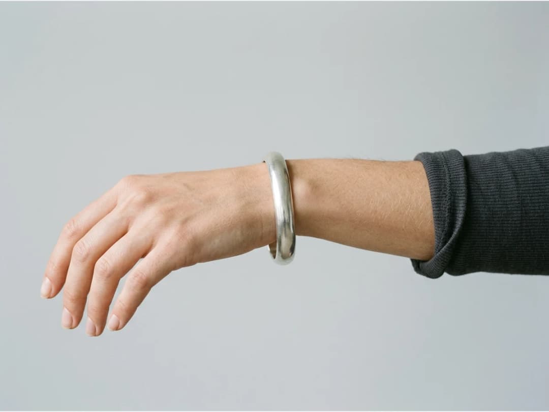 a close shot of a wrist wearing a bracelet, a silver cuff